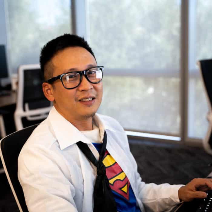 A Kingsmen employee working on his computer at his desk dressed up as Clark Kent on Halloween